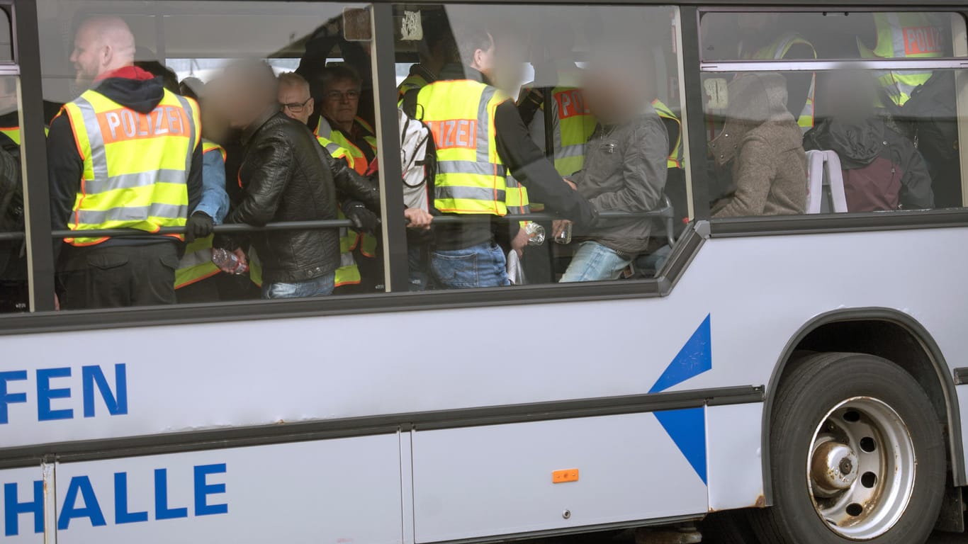 Bundespolizisten in neongelben Westen begleiten abgelehnte Asylbwerber aus Tunesien auf dem Flughafen Leipzig/Halle zum Flugzeug.