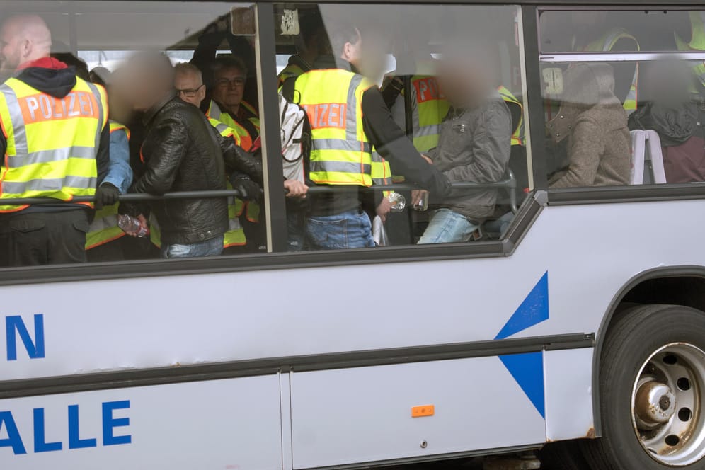 Bundespolizisten in neongelben Westen begleiten abgelehnte Asylbwerber aus Tunesien auf dem Flughafen Leipzig/Halle zum Flugzeug.