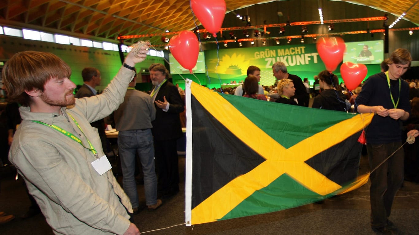 Grüne Anhänger der Jamaika-Koalition halten auf einem Parteitag eine Landesfahne hoch. Derzeit regiert in Schleswig-Holstein eine Landesregierung aus CDU, Grünen und FDP.