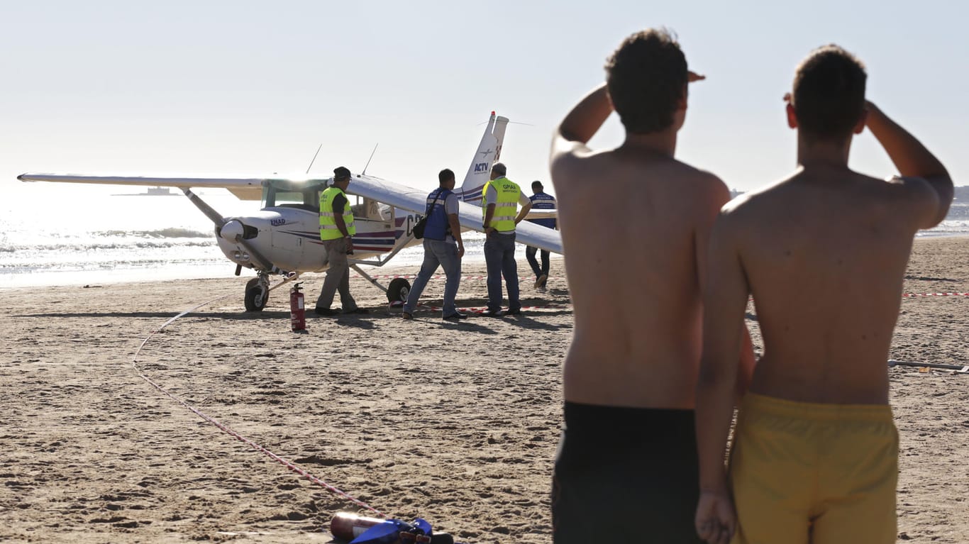 Urlauber schauen am Strand von São João da Caparica auf das Kleinflugzeug, das bei einer Notlandung zwei Menschen in den Tod riss.