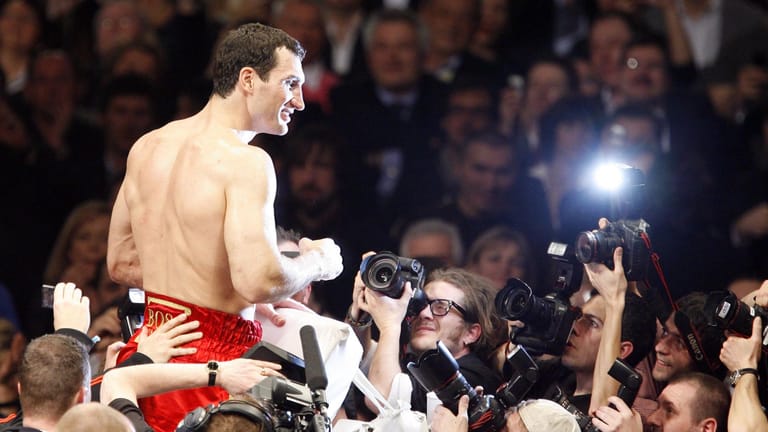 Wladimir Klitschko in bekannter Pose. Nach einem siegreichen Kampf lässt er sich im Blitzlichtgewitter von seinen Fans feiern