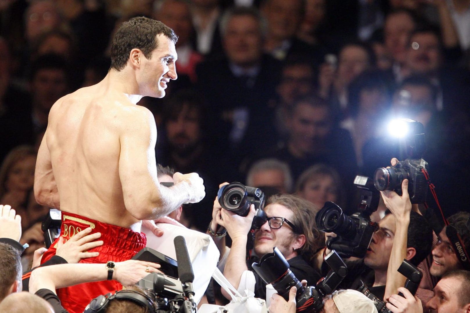 Wladimir Klitschko in bekannter Pose. Nach einem siegreichen Kampf lässt er sich im Blitzlichtgewitter von seinen Fans feiern