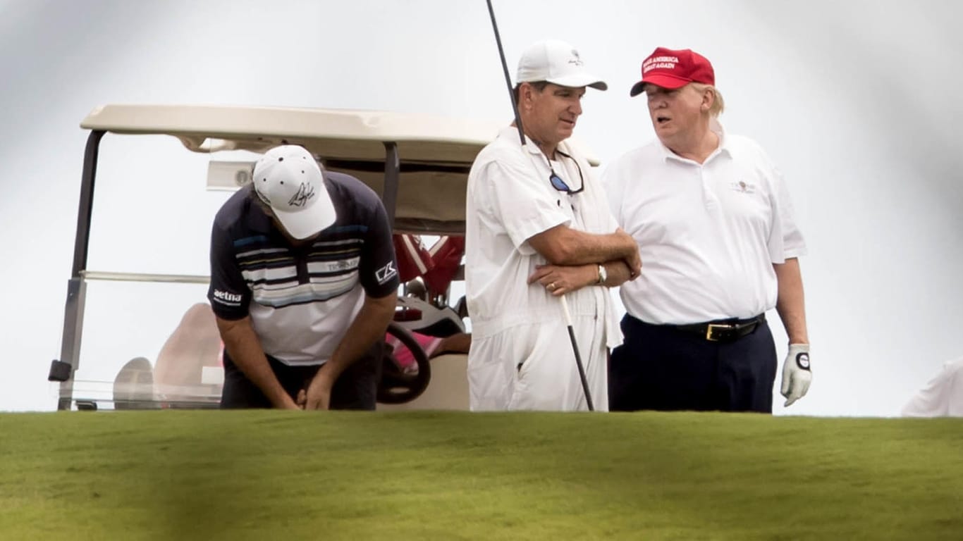 US-Präsident Donald Trump unterhält sich während einer Runde Golf auf dem Trump International Golf Club in West Palm Beach mit einem Caddie.