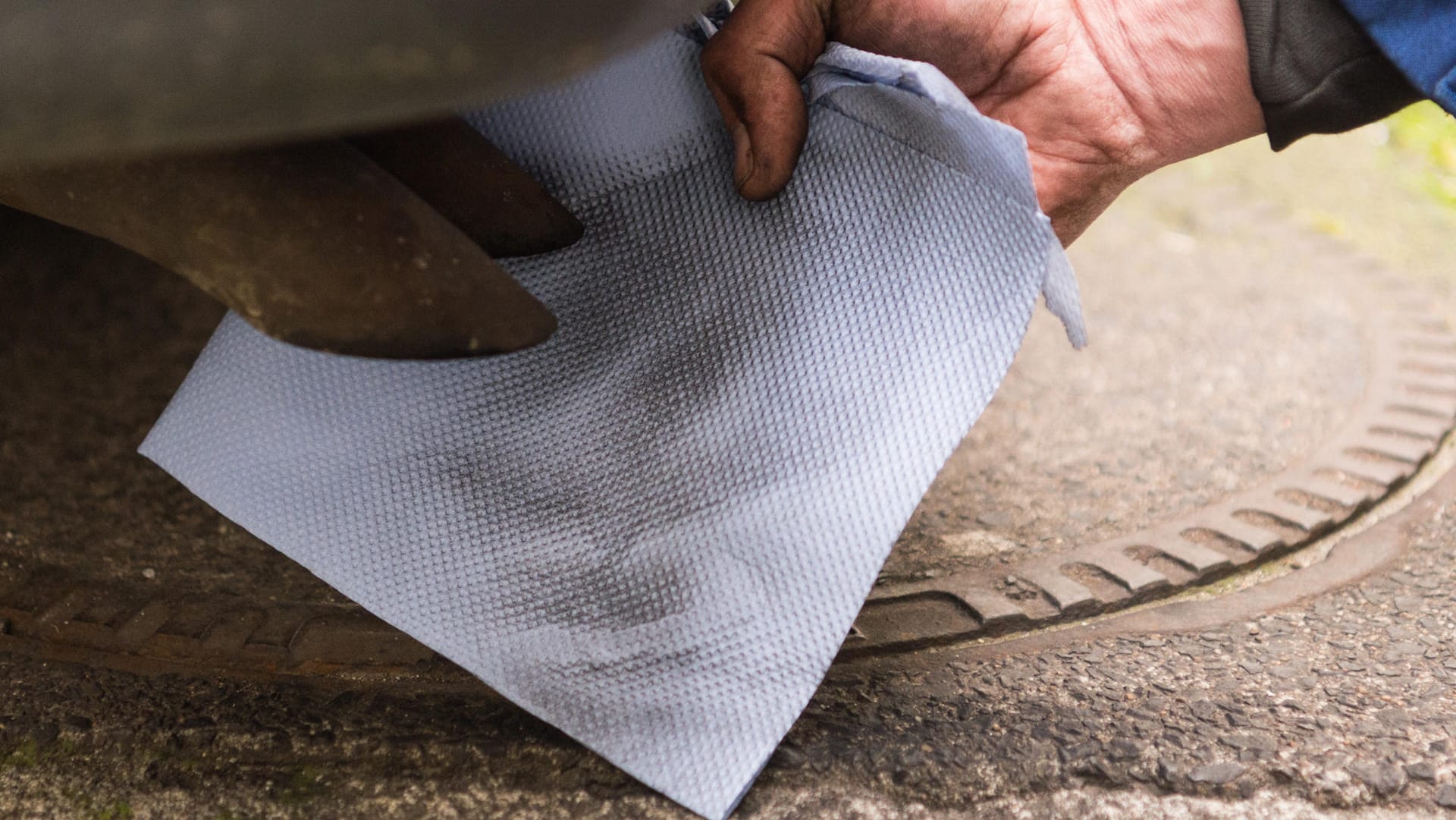 Ein Mechaniker hält ein Stück Papier vor einen Auspuff eines Dieselfahrzeugs. Ein Mechaniker hält ein Stück Papier vor einen Auspuff eines Dieselfahrzeugs.