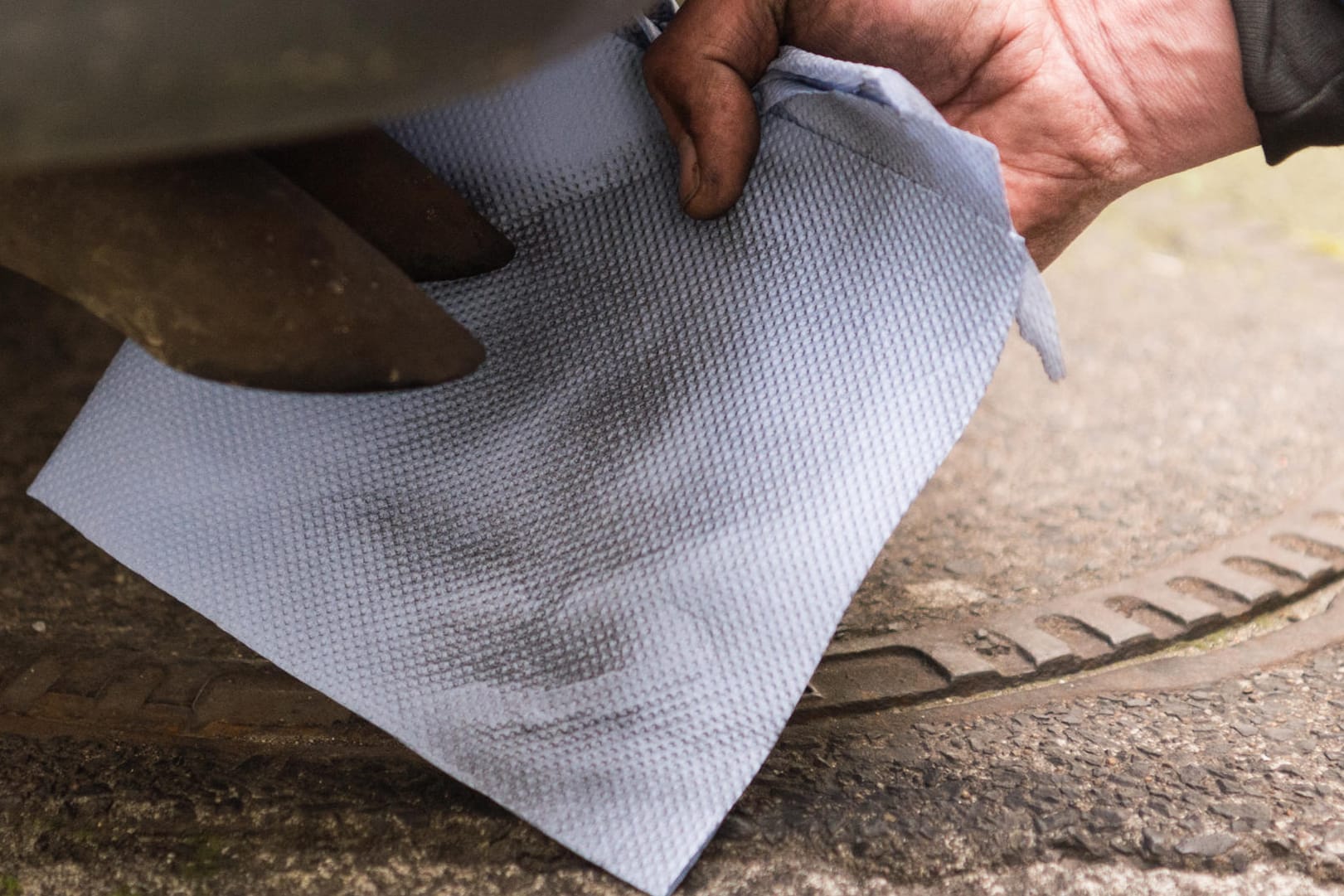 Ein Mechaniker hält ein Stück Papier vor einen Auspuff eines Dieselfahrzeugs.