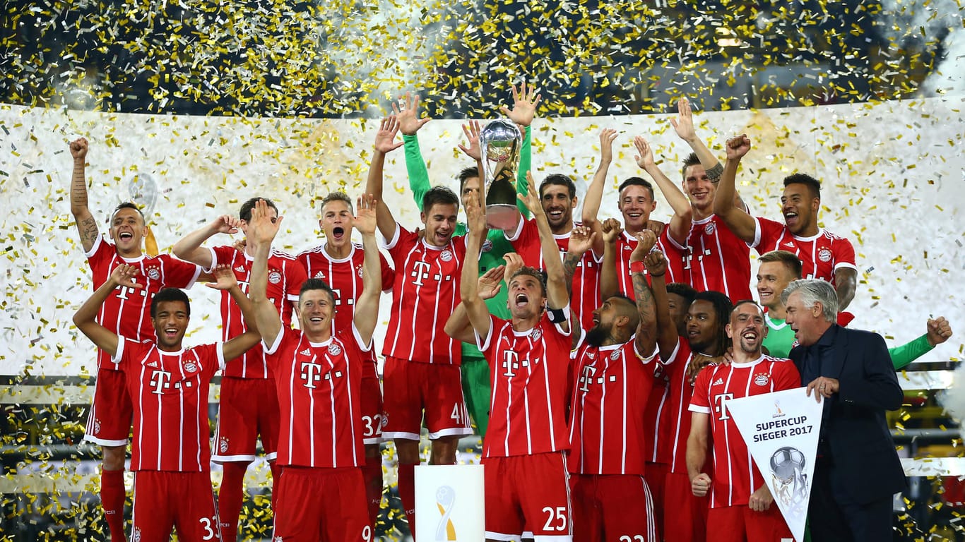 Bayerns Thomas Müller (vo.) präsentiert den Pokal.