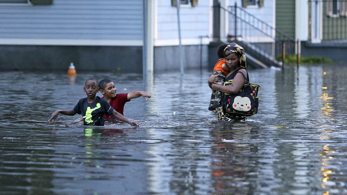 Menschen kämpfen sich in Metairie, New Orleans (USA) durch eine überflutete Straße.