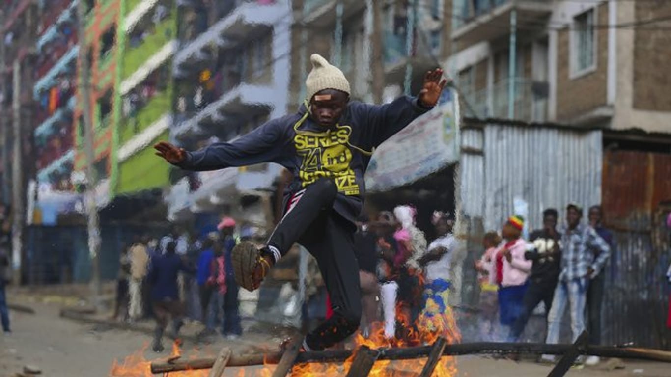 Flucht aus der Gefahrenzone: Ein Anhänger des kenianischen Oppositionsführers Odinga springt über eine brennende Barrikade.