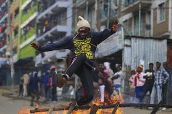 Flucht aus der Gefahrenzone: Ein Anhänger des kenianischen Oppositionsführers Odinga springt über eine brennende Barrikade.