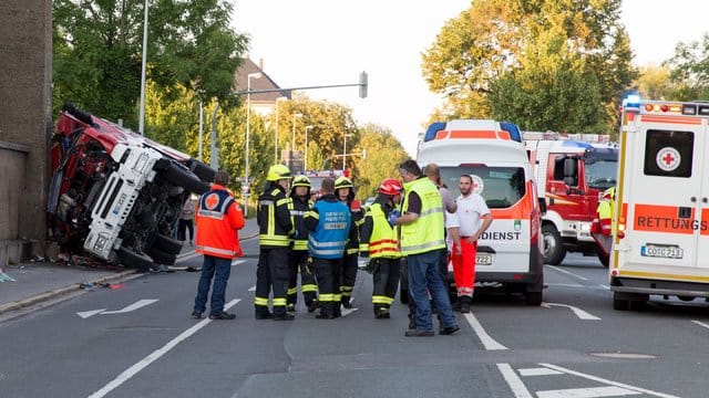 Feuerwehrleute und Rettungssanitäter stehen an einer Unfallstelle, an der ein Feuerwehrfahrzeug gegen eine Hauswand geprallt war. Feuerwehrleute und Rettungssanitäter stehen an einer Unfallstelle, an der ein Feuerwehrfahrzeug gegen eine Hauswand geprallt war.