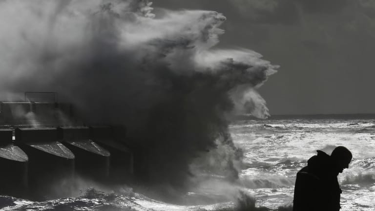 Schwarz-Weiß-Foto eines Mannes vor stürmischer See