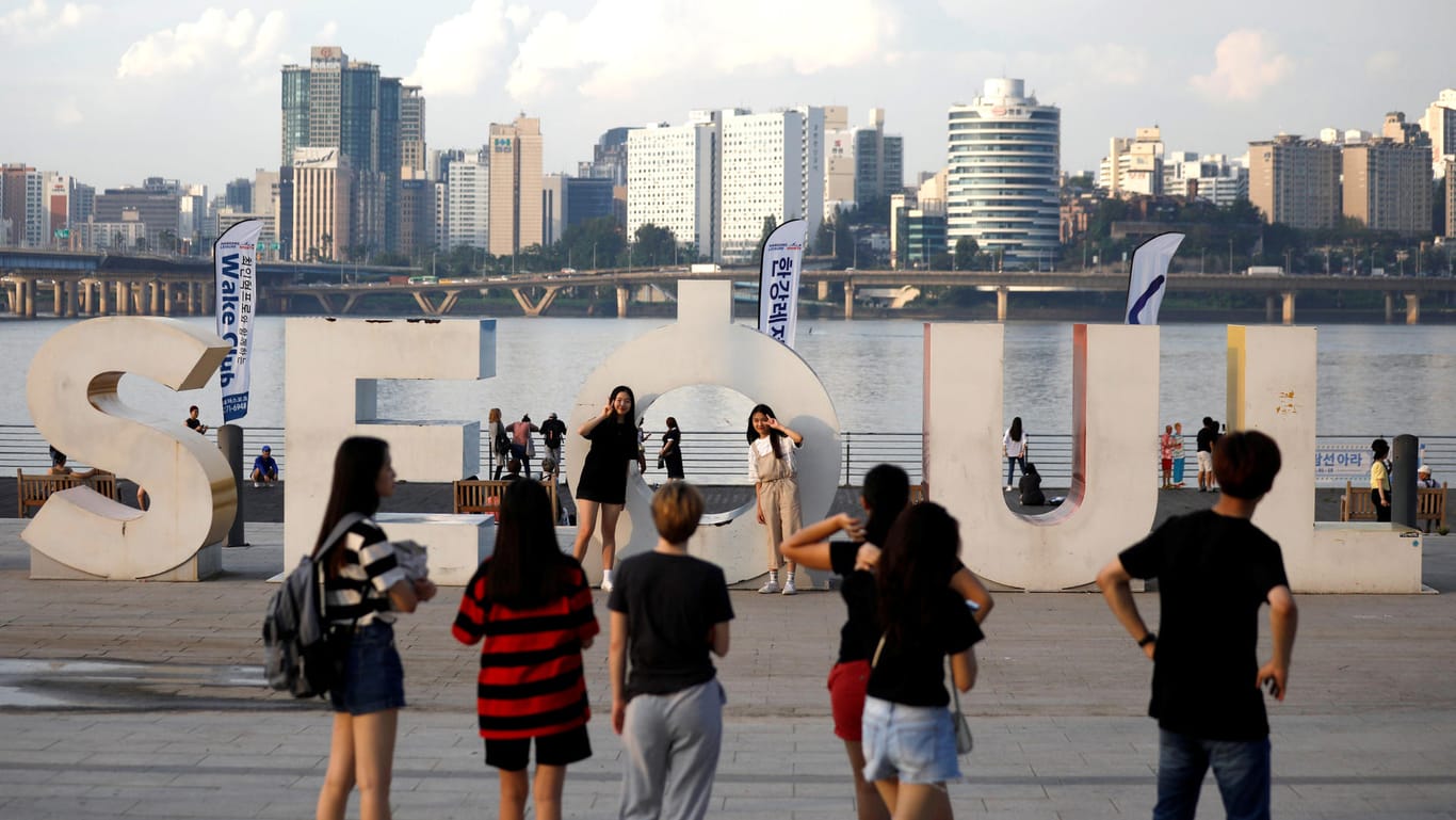 Touristen posieren am Ufer des Han-Flusses in Seoul für Fotos.