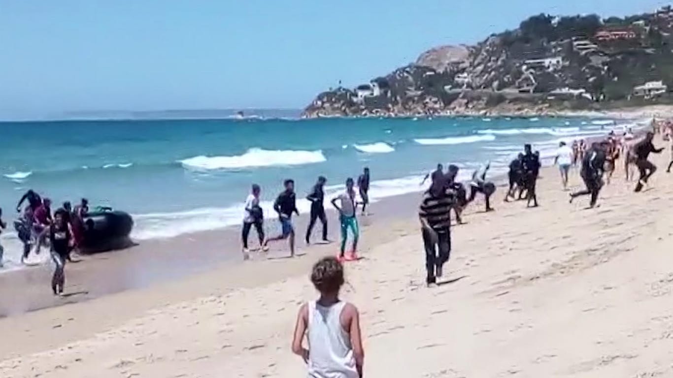 Eine Frau beobachtet, wie Flüchtlinge mit einem Schlauchboot am Strand ankommen.