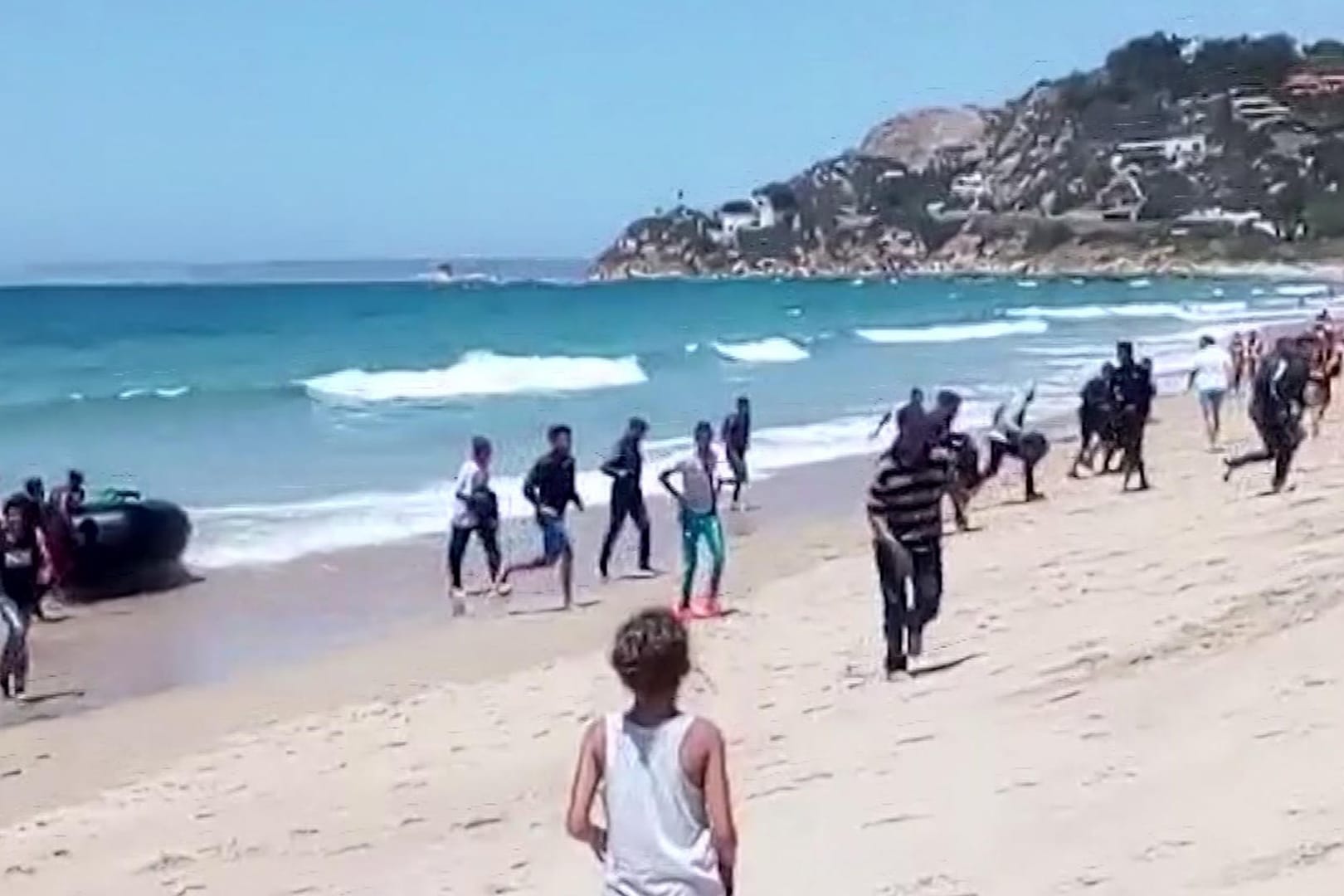 Eine Frau beobachtet, wie Flüchtlinge mit einem Schlauchboot am Strand ankommen.