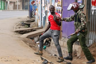 Ein Unterstützer des Oppositionsführers Odinga wird in einem Slum in Nairobi von einem Polizisten festgehalten.