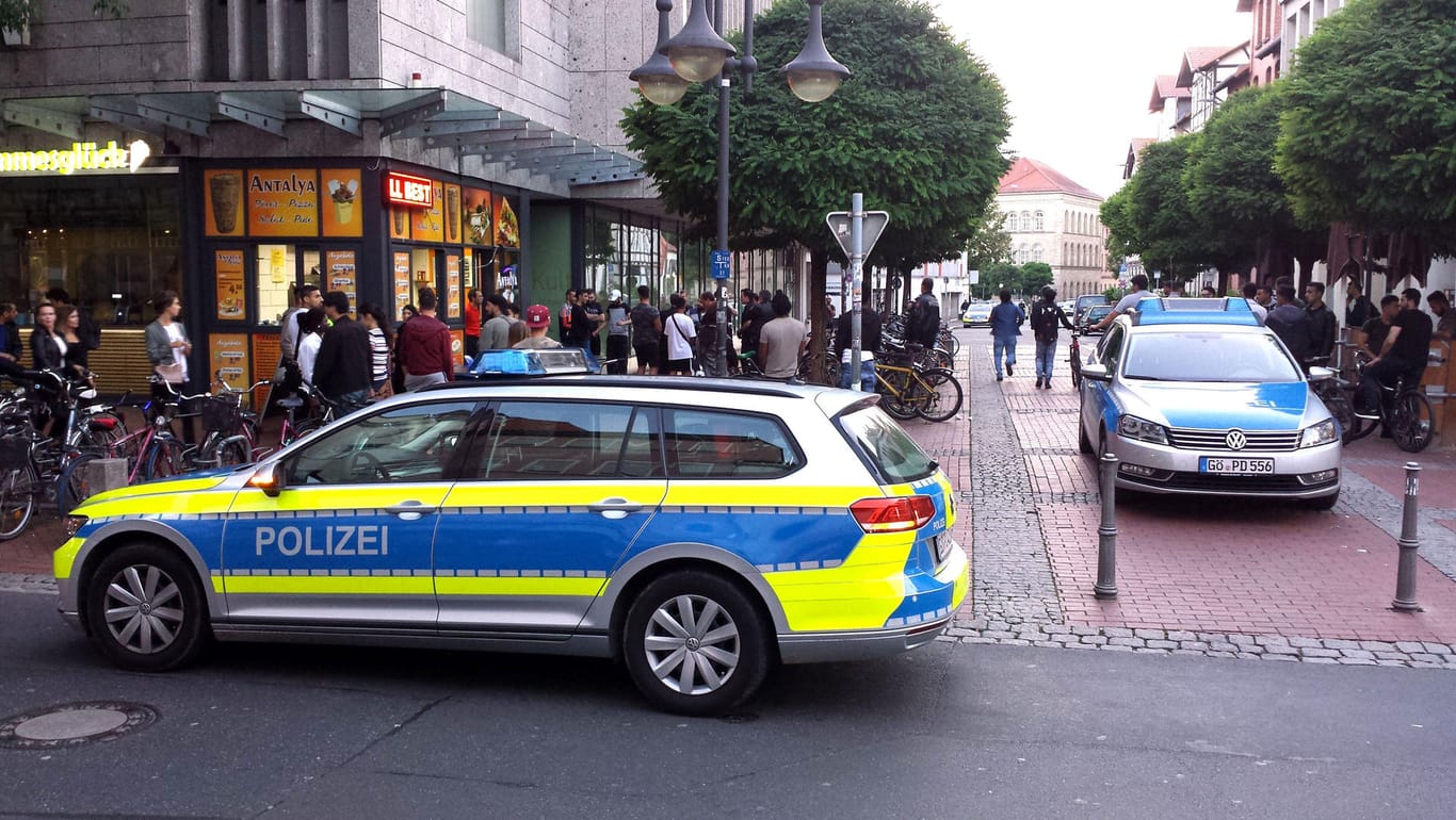 Zwei Polizeiautos stehen in der Nähe einer Gruppe Menschen vor einem Einkaufszentrum in der Innenstadt von Göttingen.