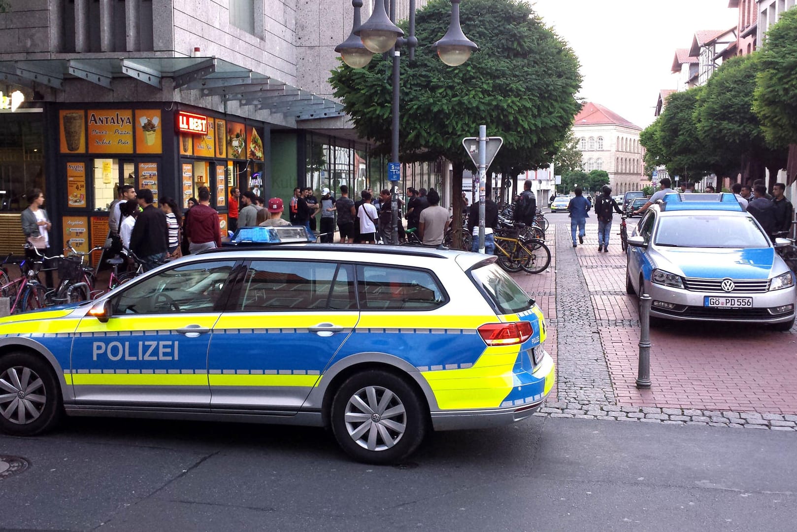 Zwei Polizeiautos stehen in der Nähe einer Gruppe Menschen vor einem Einkaufszentrum in der Innenstadt von Göttingen.