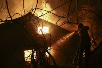 Ein Feuerwehrmann versucht ein brennendes Haus zu löschen.