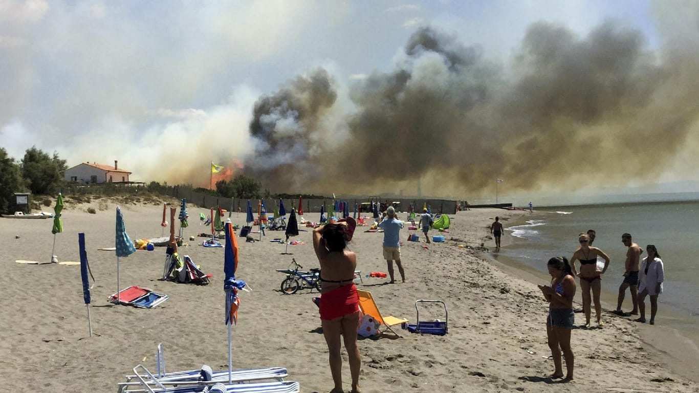 Strandbesucher beobachten bei Capalbio einen Brand auf einem Campingplatz. In Italien ist in vier Wochen fast so viel Waldfläche verbrannt wie im gesamten letzten Jahr.