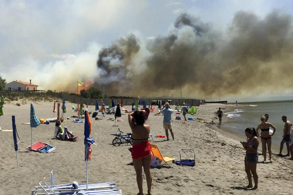 Strandbesucher beobachten bei Capalbio einen Brand auf einem Campingplatz. In Italien ist in vier Wochen fast so viel Waldfläche verbrannt wie im gesamten letzten Jahr.
