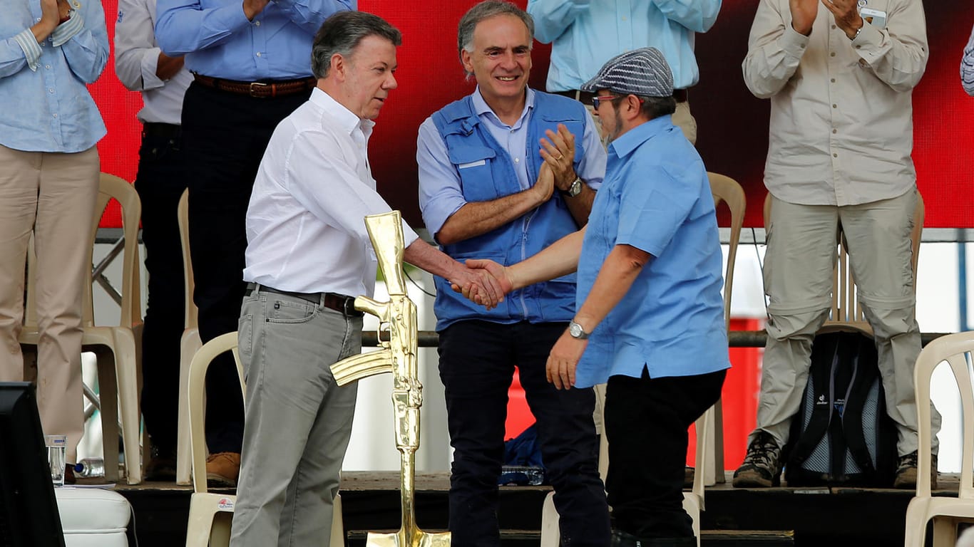 Kolumbiens Präsident Juan Manuel Santos (l.), Farc-Anführer Rodrigo Londono (r.), sowie der UN-Sondergesandte für Kolumbien, Jean Arnault (Mitte), bei einer Kundgebung im Juni in Mesetas.