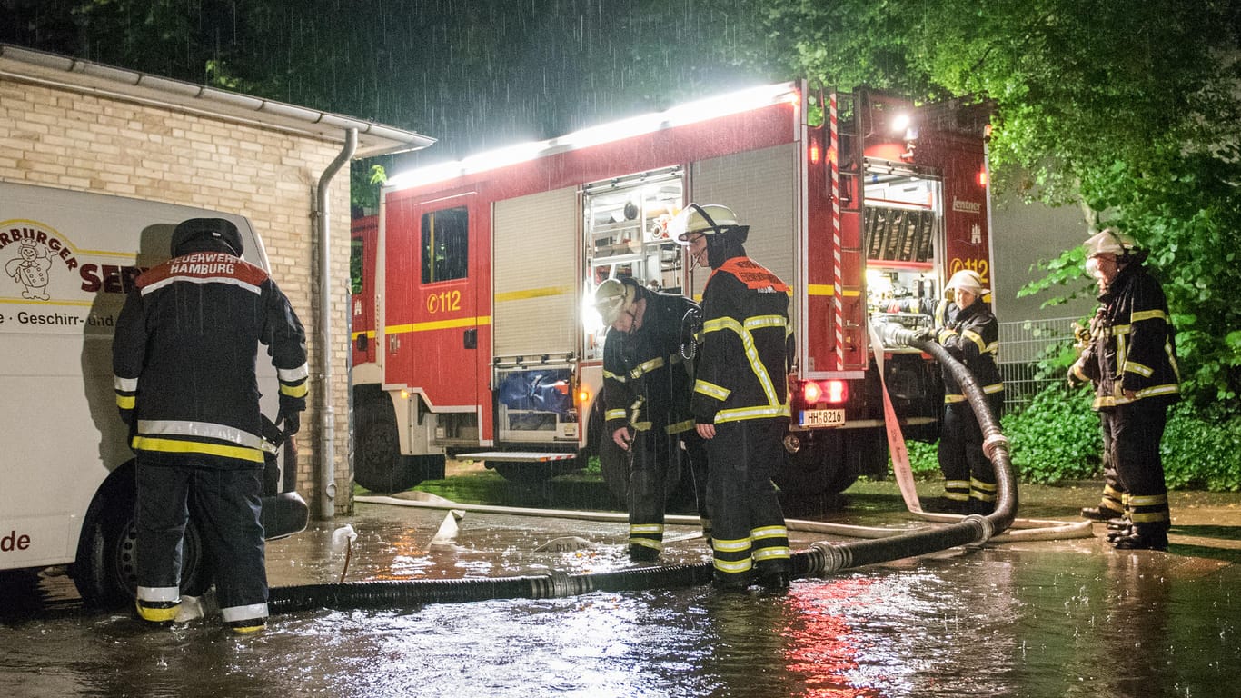 Feuerwehrleute pumpen nach dem Unwetter in Hamburg-Harburg Wasser ab.