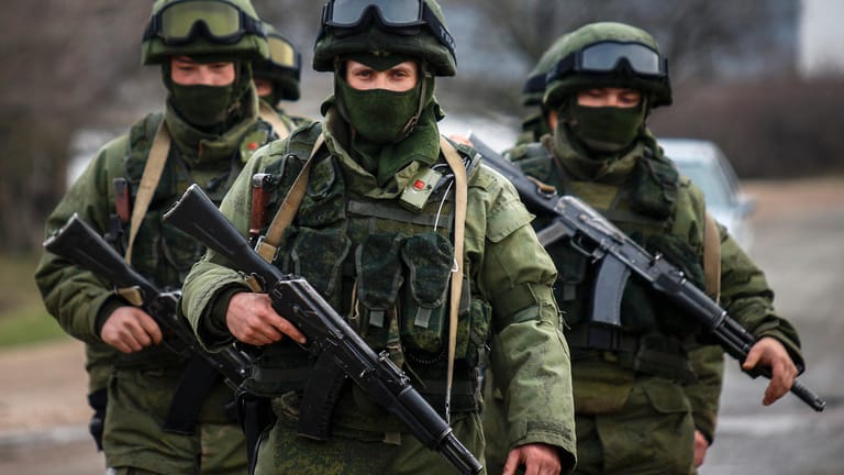 Armed men, believed to be Russian servicemen, march outside an Ukrainian military base in the village of Perevalnoye