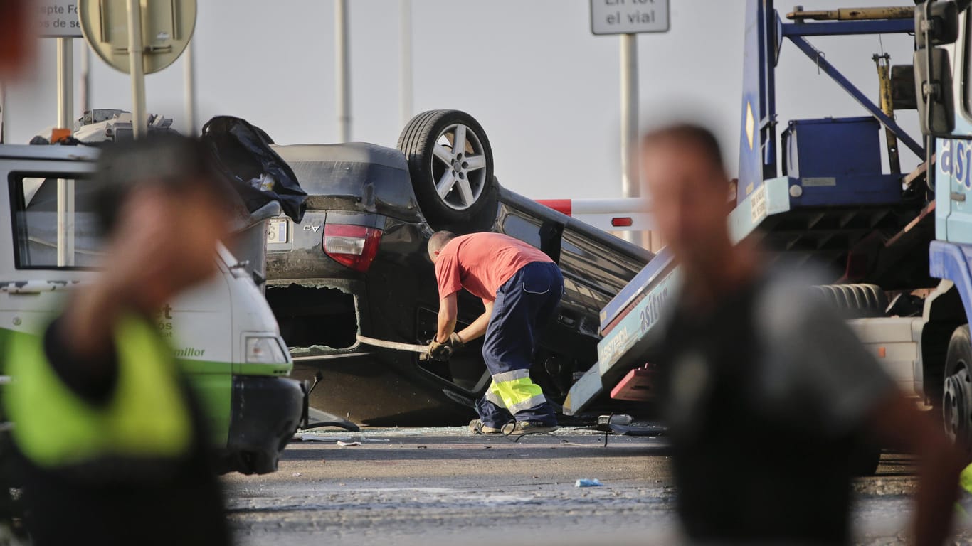 Ein Mann läd in Cambrils ein auf dem Dach liegendes Auto auf einen Abschleppwagen, an der Stelle wo Polizisten fünf Terroristen abgefangen hatten.