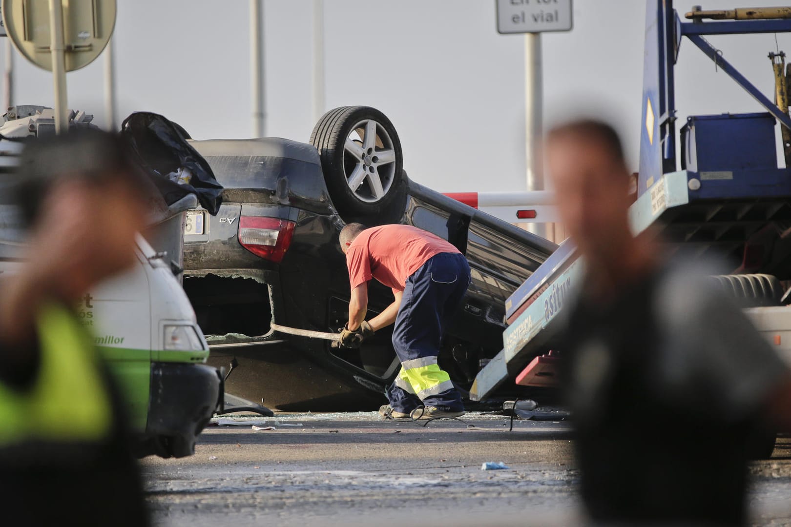 Ein Mann läd in Cambrils ein auf dem Dach liegendes Auto auf einen Abschleppwagen, an der Stelle wo Polizisten fünf Terroristen abgefangen hatten.