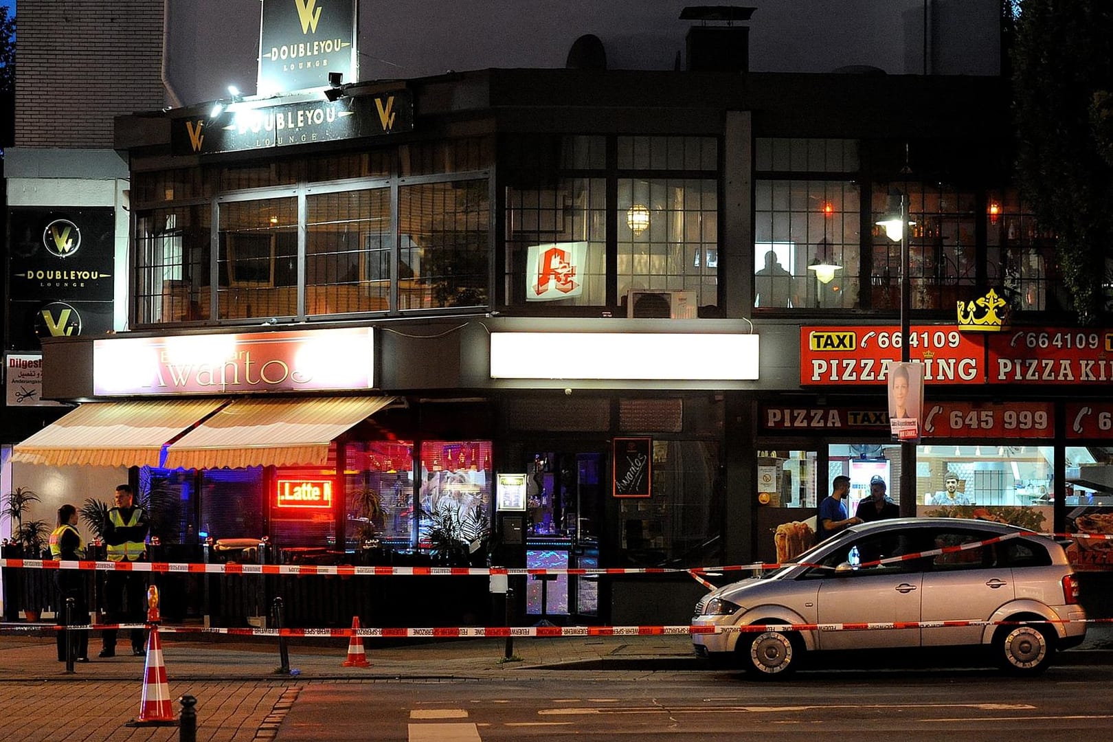 Polizisten stehen in einem mit Flatterband abgesperrten Bereich vor einem Bistro in Wuppertal, wo ein Mann lebensgefährlich verletzt worden ist.