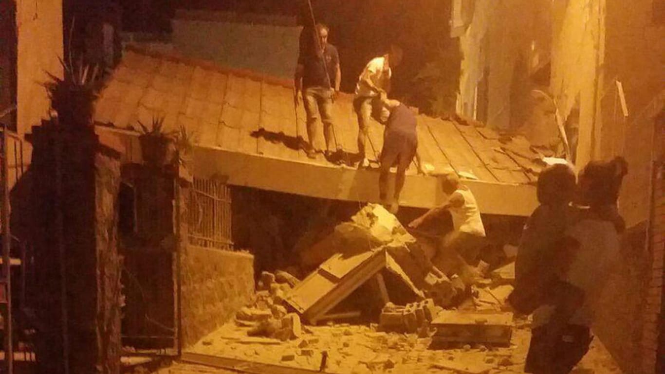 Ein Erdbeben hat die italienische Urlaubsinsel Ischia erschüttert. Betroffene Menschen räumen Schutt von einem Gebäude.