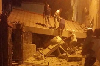 Ein Erdbeben hat die italienische Urlaubsinsel Ischia erschüttert. Betroffene Menschen räumen Schutt von einem Gebäude.