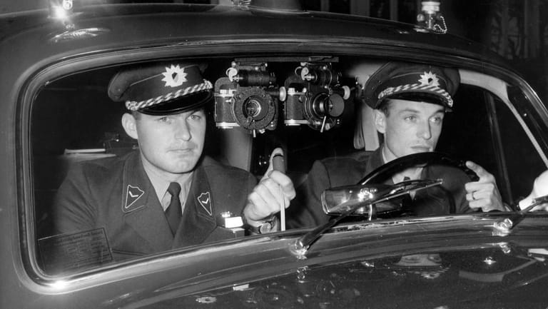 Mit zwei an der Windschutzscheibe ihres Polizeifahrzeuges installierten Kameras sind zwei Polizisten im Oktober 1958 in Stuttgart den Temposündern auf der Spur. Die Kameras werden vom Beifahrer bedient und können einzeln, gleichzeitig und bei Nacht zusammen mit Blitzlicht ausgelöst werden.