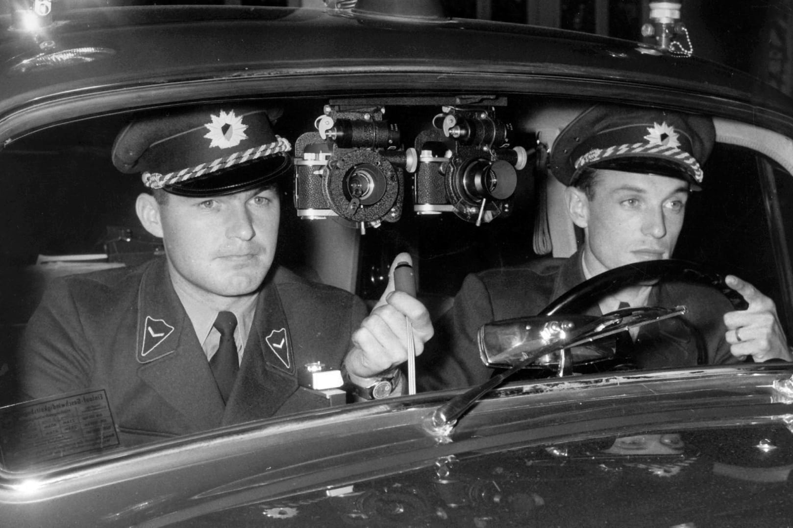 Mit zwei an der Windschutzscheibe ihres Polizeifahrzeuges installierten Kameras sind zwei Polizisten im Oktober 1958 in Stuttgart den Temposündern auf der Spur. Die Kameras werden vom Beifahrer bedient und können einzeln, gleichzeitig und bei Nacht zusammen mit Blitzlicht ausgelöst werden.