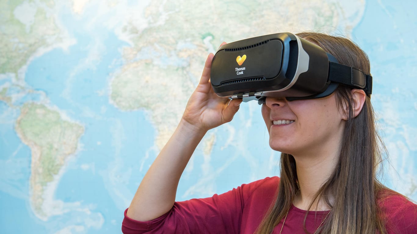 Eine Frau schaut sich mit einer VR-Brille in einem Reisebüro potenzielle Reiseziele an.