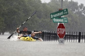 In Houston rudern zwei Männer bei heftigem Regen auf einer überfluteten Straße.