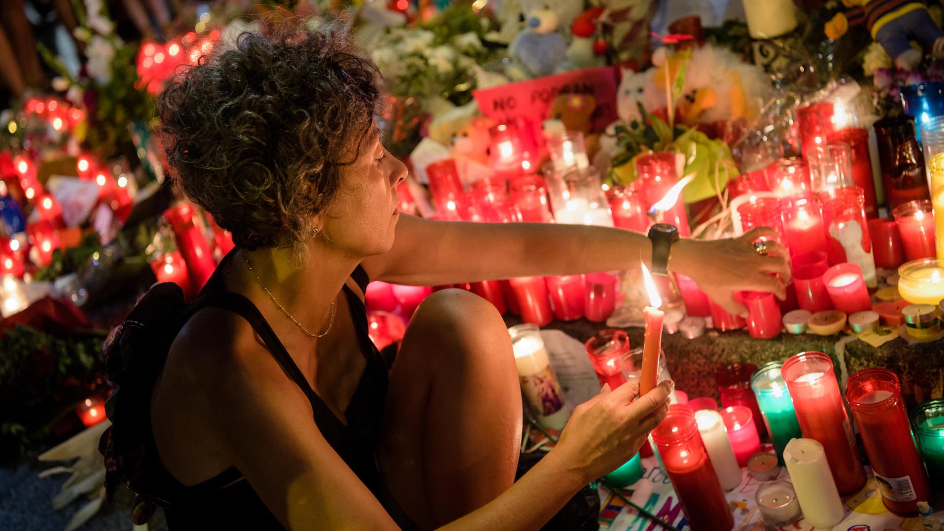 Eine Frau zündet auf der Flaniermeile Las Ramblas in Barcelona Kerzen für die Opfer des Anschlags an.