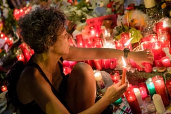 Eine Frau zündet auf der Flaniermeile Las Ramblas in Barcelona Kerzen für die Opfer des Anschlags an.