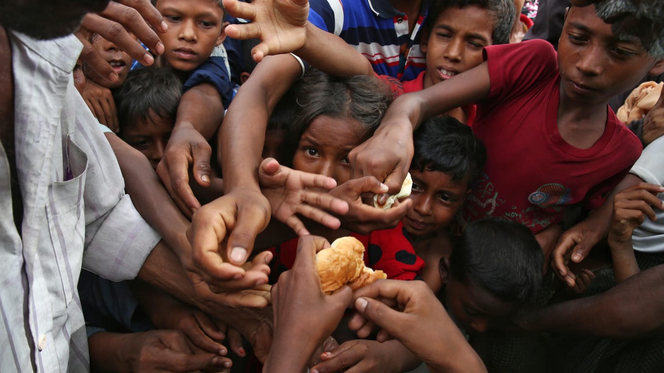Flüchtlingskinder, der muslimischen Minderheit der Rohingyas, greifen in einem Flüchtlingslager in Bangladesch nach Etwas zu essen.