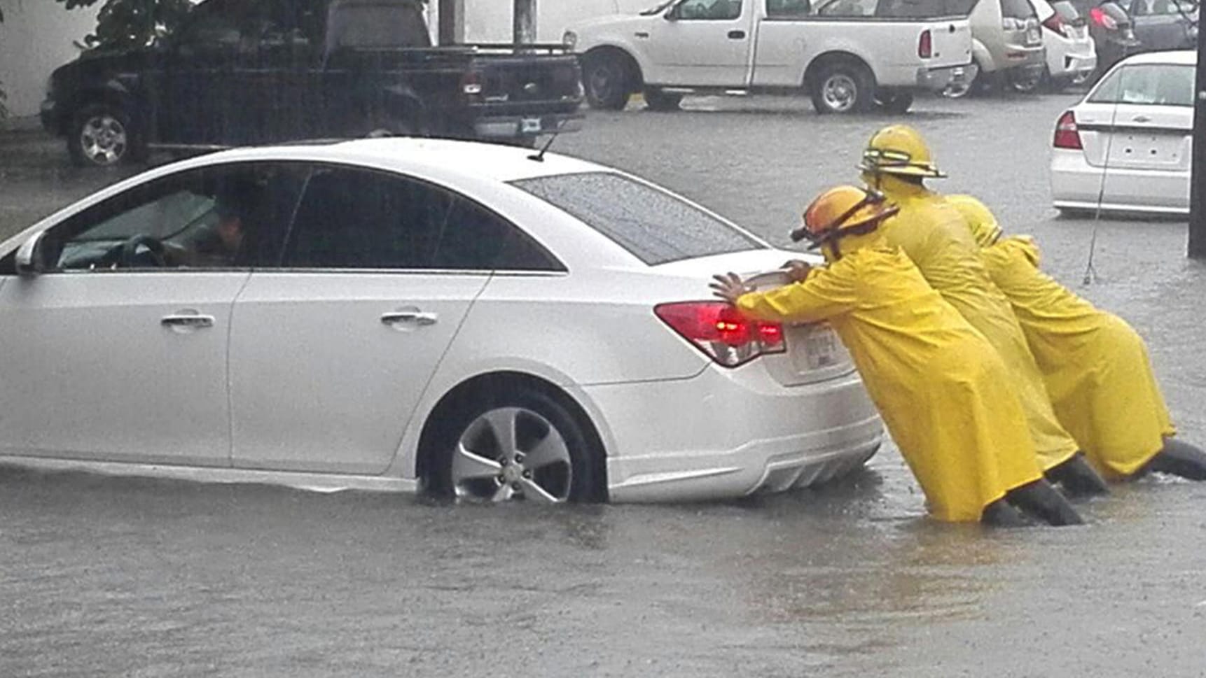 Drei Männer schieben amin Cancun (Mexiko) ein Auto von einer überschwemmten Straße. Hurrikan «Irma» hat mit starken Regenfällen vielerorts zu Überschwemmungen geführt.