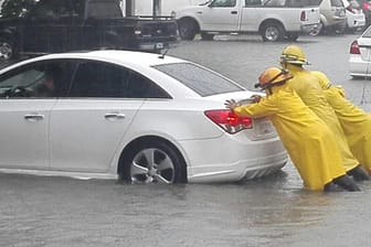 Drei Männer schieben amin Cancun (Mexiko) ein Auto von einer überschwemmten Straße. Hurrikan «Irma» hat mit starken Regenfällen vielerorts zu Überschwemmungen geführt.