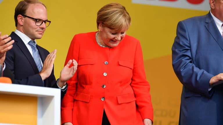 Kanzlerin Angela Merkel schaut in Heidelberg auf dem Universitätsplatz bei einer Wahlkampfveranstaltung auf einen Fleck auf ihrer Jacke.