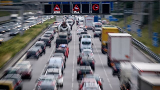 Zähfließender Verkehr während auf einer Anzeigetafel über der Autobahn vor Stau gewarnt wird.