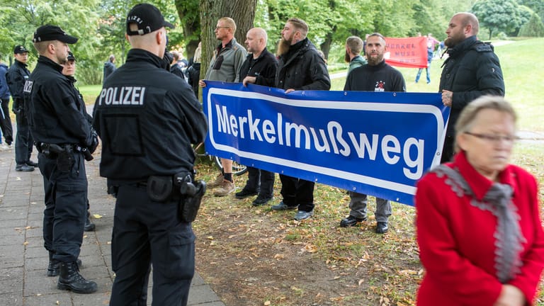 Merkel-Gegner stehen mit Transparenten am Rand der CDU-Wahlkampfveranstaltung in Strasburg.
