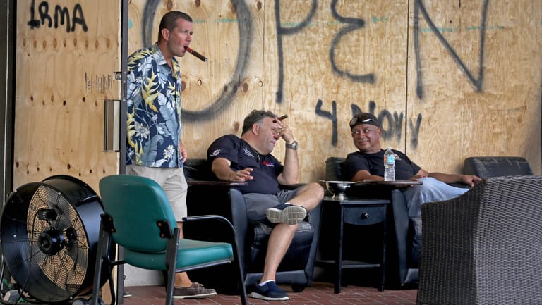 Todd Tarczynski (l-r), Harris Safra und William Brown rauchen vor der Bar gemeinsam eine Zigarre.