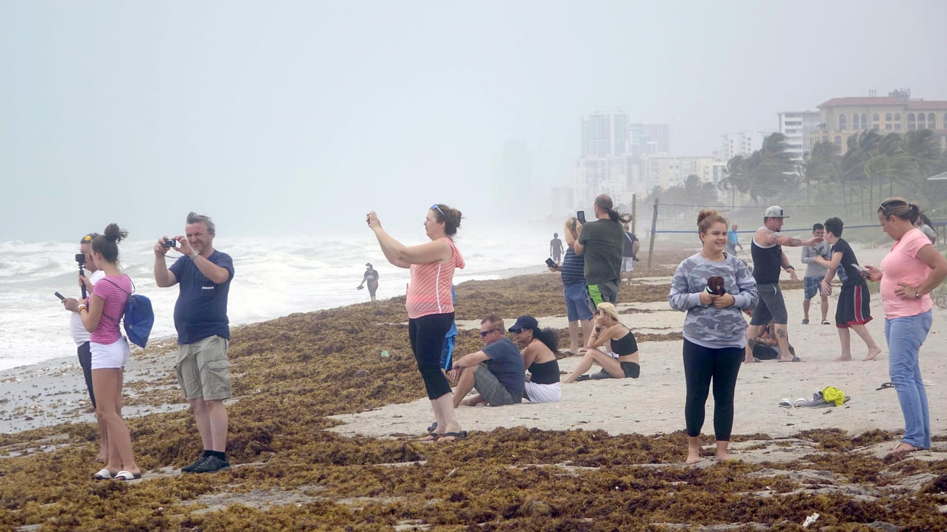 An einem Strand in Florida fotografieren Schaulustige die hohen Wellen.