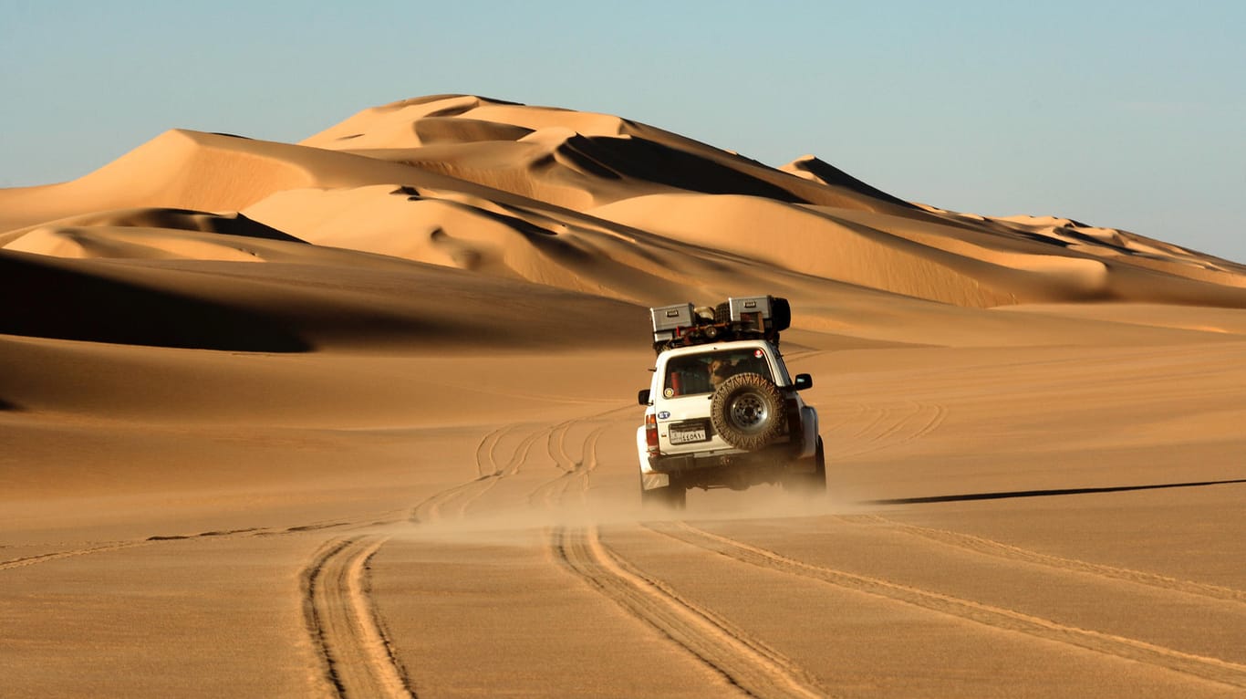 Ein Geländewagen einer Wüstenexpedition bei der Fahrt durch die Wüstenlandschaft der Sahara.
