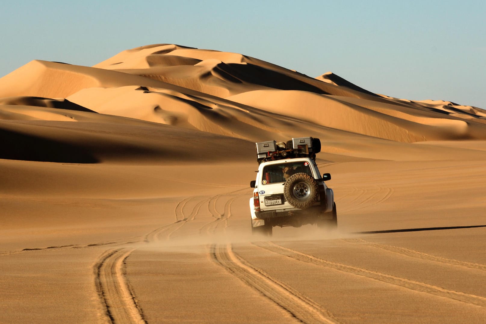Ein Geländewagen einer Wüstenexpedition bei der Fahrt durch die Wüstenlandschaft der Sahara.