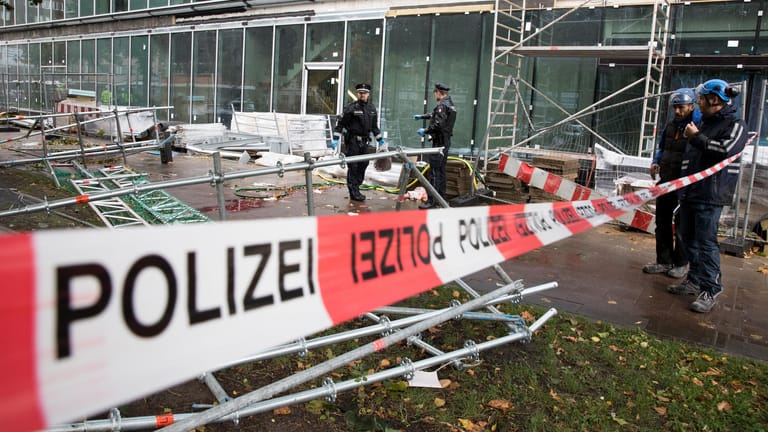 Polizeibeamte sichern in Hamburg die persöhnlichen Gegenstände und Bekleidung eines verletzten Passanten an der Unglücksstelle. Ein umgestürztes Baugerüst hat einen Passanten lebensgefährlich verletzt.