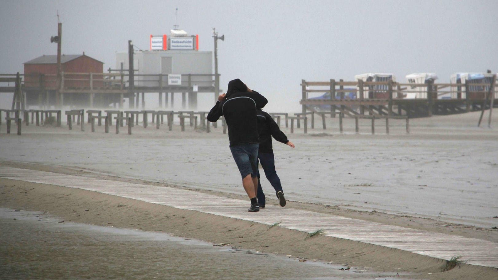 Spaziergänger stemmen sich am Strand von St. Peter-Ording (Schleswig-Holstein) gegen den ersten Herbststurm des Jahres.